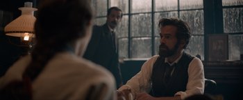 Movie still from “Eiffel” (2021), directed by Martin Bourboulon – A man in a suit and tie sitting in front of another man in a suit and tie; Medium shot, Over the shoulder angle