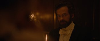 Movie still from “Eiffel” (2021), directed by Martin Bourboulon – A man with a beard wearing a suit and bow tie; Close Up shot, Over the shoulder angle