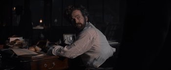 Movie still from “Eiffel” (2021), directed by Martin Bourboulon – A man sitting at a desk in a dark room; Medium shot, Low angle