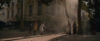 Movie still from “Eiffel” (2021), directed by Martin Bourboulon – A group of people standing in the middle of a street; Extreme Wide shot, High angle