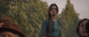 Movie still from “Eiffel” (2021), directed by Martin Bourboulon – A woman with a braid standing in front of trees; Close Up shot, Over the shoulder angle