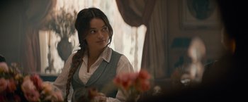 Movie still from “Eiffel” (2021), directed by Martin Bourboulon – A woman sitting in front of a table with flowers; Close Up shot, Over the shoulder angle