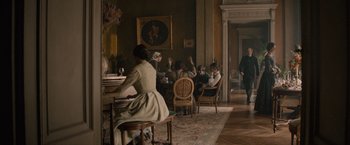 Movie still from “Eiffel” (2021), directed by Martin Bourboulon – A group of people sitting at a table in a room; Wide shot, Over the shoulder angle
