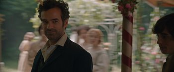 Movie still from “Eiffel” (2021), directed by Martin Bourboulon – A man standing next to a woman in a black suit; Close Up shot, Over the shoulder angle