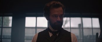 Movie still from “Eiffel” (2021), directed by Martin Bourboulon – A man with a beard wearing a vest and a tie; Close Up shot, Low angle