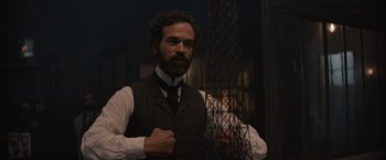 Movie still from “Eiffel” (2021), directed by Martin Bourboulon – A man with a beard wearing a vest and a tie; Medium shot, Low angle