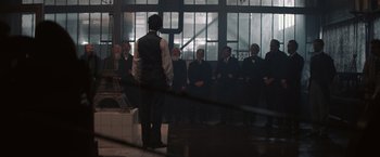 Movie still from “Eiffel” (2021), directed by Martin Bourboulon – A group of men in suits standing in front of a building; Wide shot, Low angle