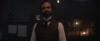 Movie still from “Eiffel” (2021), directed by Martin Bourboulon – A man with a beard wearing a vest and a tie; Medium shot, Over the shoulder angle