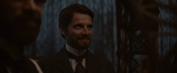 Movie still from “Eiffel” (2021), directed by Martin Bourboulon – A person wearing a suit and tie; Close Up shot, Over the shoulder angle