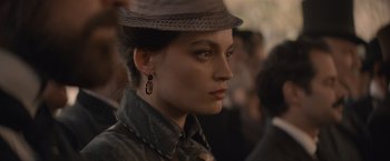 Movie still from “Eiffel” (2021), directed by Martin Bourboulon – A person wearing a hat and looking to the side; Close Up shot, Over the shoulder angle