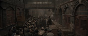 Movie still from “Eiffel” (2021), directed by Martin Bourboulon – A group of people standing around a building; Extreme Wide shot, High angle