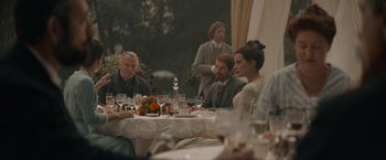 Movie still from “Eiffel” (2021), directed by Martin Bourboulon – A group of people sitting at a table with wine glasses; Wide shot, Over the shoulder angle