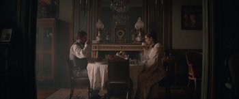 Movie still from “Eiffel” (2021), directed by Martin Bourboulon – A man and a woman sitting at a dinner table; Wide shot, High angle