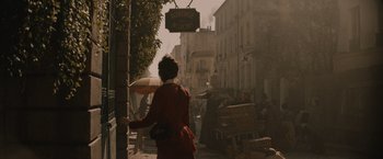Movie still from “Eiffel” (2021), directed by Martin Bourboulon – A woman walking down the street holding an umbrella; Wide shot, Over the shoulder angle