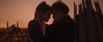 Movie still from “Eiffel” (2021), directed by Martin Bourboulon – A man and a woman embracing in front of a sunset; Close Up shot, Low angle