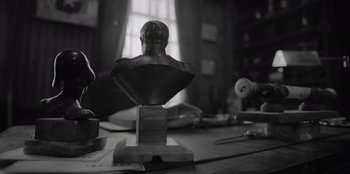 Movie still from “El Conde” (2023), directed by Pablo Larraín – A black and white photo of a bust on a table; Close Up shot, Low angle