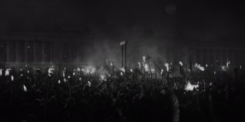 Movie still from “El Conde” (2023), directed by Pablo Larraín – A crowd of people standing in front of a building at night; Extreme Wide shot, High angle