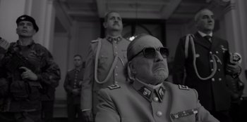 Movie still from “El Conde” (2023), directed by Pablo Larraín – A man in a military uniform and sunglasses; Medium shot, Low angle