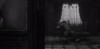 Movie still from “El Conde” (2023), directed by Pablo Larraín – An old man sitting on a chair in a room; Wide shot, Low angle