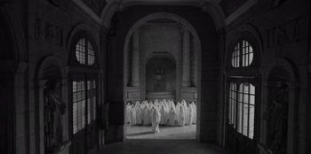 Movie still from “El Conde” (2023), directed by Pablo Larraín – A black and white photo of a group of people dressed in white in an archway; Extreme Wide shot, High angle