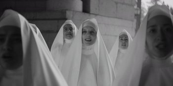 Movie still from “El Conde” (2023), directed by Pablo Larraín – A group of women dressed as nuns in front of a brick wall; Medium shot, Low angle