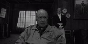 Movie still from “El Conde” (2023), directed by Pablo Larraín – An older man wearing a jacket in front of another man in a suit; Medium shot, Over the shoulder angle