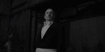 Movie still from “El Conde” (2023), directed by Pablo Larraín – A man in a suit and bow tie standing in front of a wall; Medium shot, Low angle