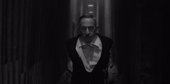Movie still from “El Conde” (2023), directed by Pablo Larraín – An old man in a suit and bow tie in a dark hallway; Medium shot, Low angle