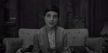 Movie still from “El Conde” (2023), directed by Pablo Larraín – A woman sitting on top of a couch with her eyes wide open; Close Up shot, High angle