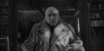 Movie still from “El Conde” (2023), directed by Pablo Larraín – An old man wearing a fur coat in a black and white photo; Close Up shot, Low angle