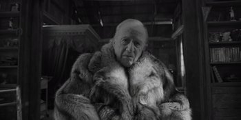 Movie still from “El Conde” (2023), directed by Pablo Larraín – An old man wearing a fur coat sitting in a chair; Close Up shot, Low angle