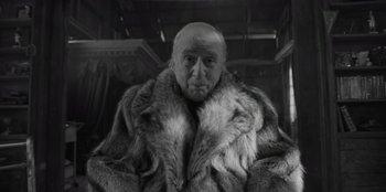 Movie still from “El Conde” (2023), directed by Pablo Larraín – An old man wearing a fur coat in a black and white photo; Close Up shot, Low angle