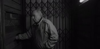 Movie still from “El Conde” (2023), directed by Pablo Larraín – An older man standing in front of a metal gate; Medium shot, Low angle