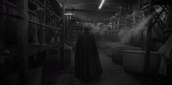 Movie still from “El Conde” (2023), directed by Pablo Larraín – A man wearing a black cape and a black hat; Wide shot, High angle