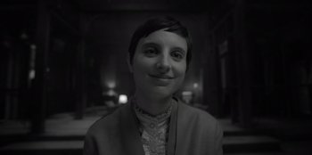 Movie still from “El Conde” (2023), directed by Pablo Larraín – A black - and - white photo of a woman smiling; Close Up shot, Over the shoulder angle