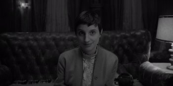 Movie still from “El Conde” (2023), directed by Pablo Larraín – A black - and - white photo of a woman sitting in front of a couch; Close Up shot, High angle