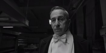 Movie still from “El Conde” (2023), directed by Pablo Larraín – An older man wearing a suit and bow tie; Close Up shot, Low angle