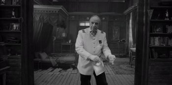 Movie still from “El Conde” (2023), directed by Pablo Larraín – An older man in a uniform playing a video game; Medium shot, High angle