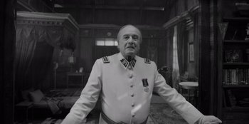 Movie still from “El Conde” (2023), directed by Pablo Larraín – An older man in a uniform standing in a room; Medium shot, Low angle
