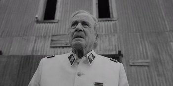 Movie still from “El Conde” (2023), directed by Pablo Larraín – An older man in a military uniform looking up; Close Up shot, Low angle