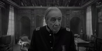 Movie still from “El Conde” (2023), directed by Pablo Larraín – An older man in a military uniform looking at the camera; Close Up shot, Over the shoulder angle