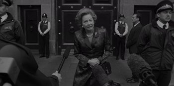 Movie still from “El Conde” (2023), directed by Pablo Larraín – An older woman is sitting in front of a group of people; Medium shot, Over the shoulder angle