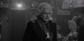 Movie still from “El Conde” (2023), directed by Pablo Larraín – An older man in a military uniform with a long white wig; Close Up shot, Over the shoulder angle