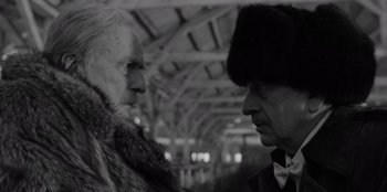 Movie still from “El Conde” (2023), directed by Pablo Larraín – A man in a fur coat and a man in a hat; Close Up shot, Low angle
