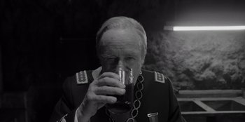 Movie still from “El Conde” (2023), directed by Pablo Larraín – An older man drinking a glass of wine; Close Up shot, Over the shoulder angle
