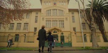 Movie still from “El Conde” (2023), directed by Pablo Larraín – A woman and a child walking in front of a building; Extreme Wide shot, Low angle
