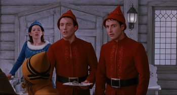 Movie still from “Elf” (2003), directed by Jon Favreau – Two men in red are standing next to each other; Medium shot, Low angle