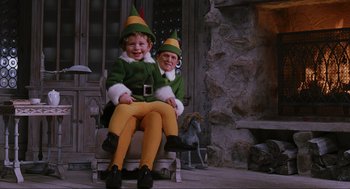 Movie still from “Elf” (2003), directed by Jon Favreau – A couple of kids sitting on top of a wooden chair; Wide shot, Low angle