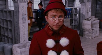 Movie still from “Elf” (2003), directed by Jon Favreau – A man wearing a red coat and a hat; Medium shot, Over the shoulder angle