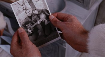 Movie still from “Elf” (2003), directed by Jon Favreau – A person holding a picture of a man and a woman; Close Up shot, Overhead angle